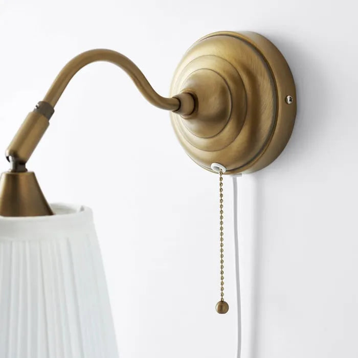 Close-up of IKEA ÅRSTID brass wall lamp shade and finish