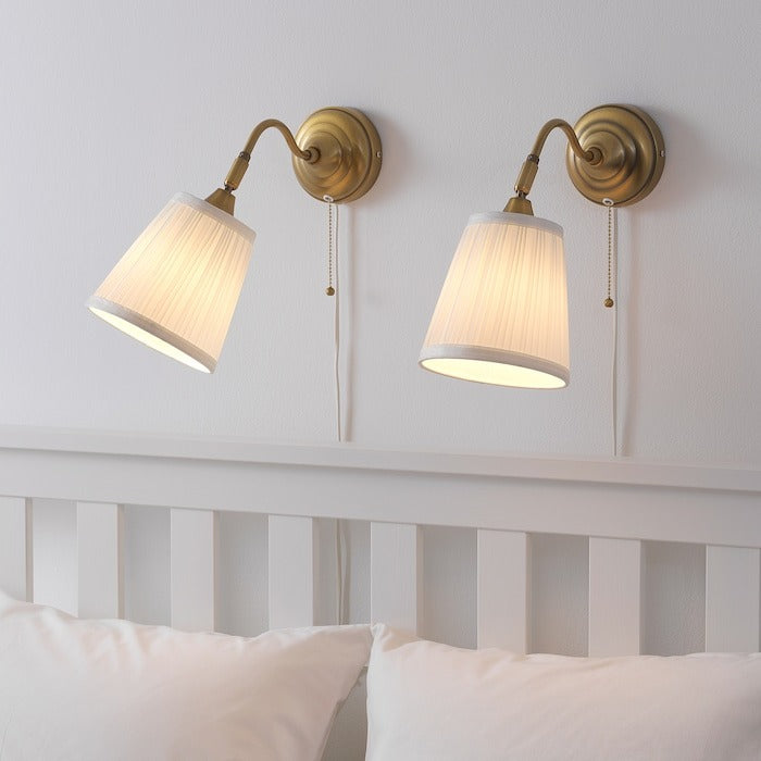 IKEA ARSTID wall lamp in gold color.