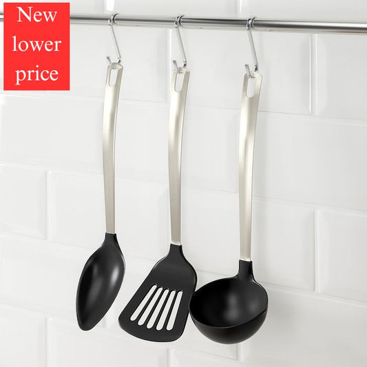 Black kitchen utensils with silver handles hanging on a rack against a white tiled wall.